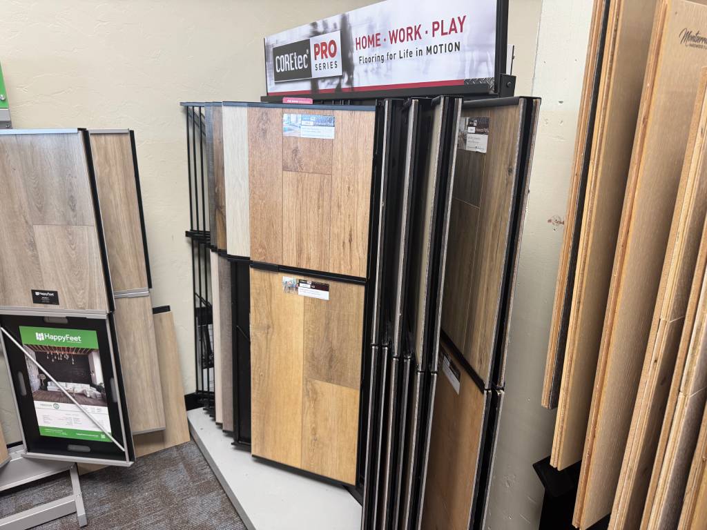 Display of COREtec Pro Series and HappyFeet luxury vinyl flooring samples with wood and tile designs at The Flooring Store & More Tucson